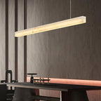 Clérachic Velmore pendant glowing above a counter against a textured dark stone wall.