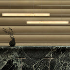 Two Clérachic Velmore pendants over a green marble counter with fluted brass panelling behind.