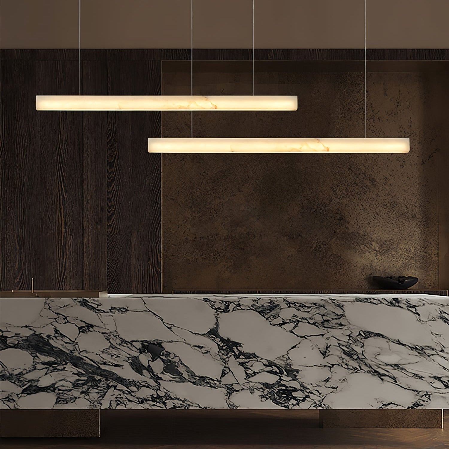 Clérachic Velmore pendants staggered above a veined marble counter and dark timber joinery.