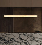 The Clérachic Velmore pendant above a marble counter set against a bronze-toned wall.