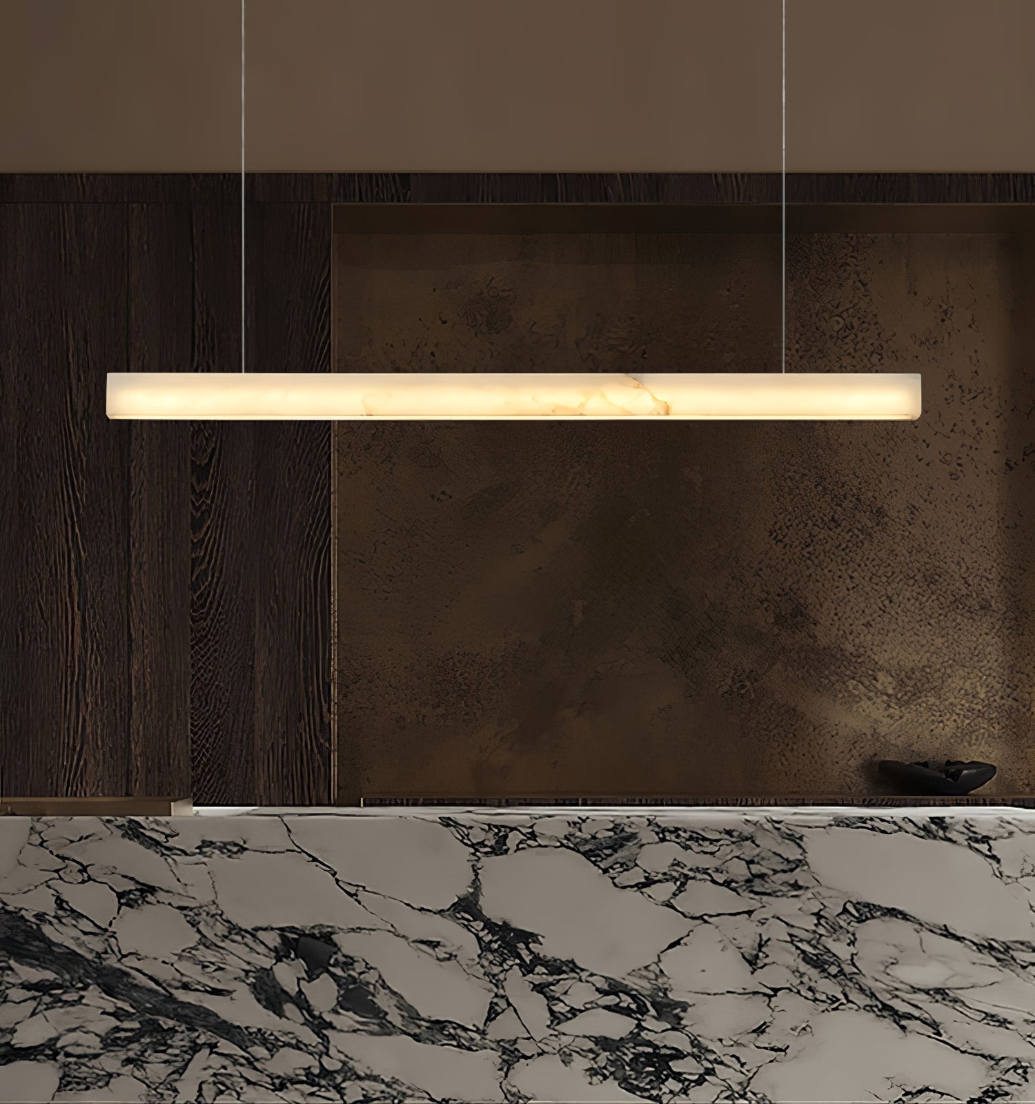 The Clérachic Velmore pendant above a marble counter set against a bronze-toned wall.
