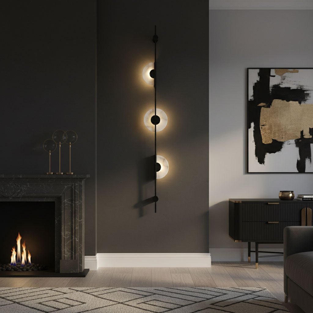 Three-disc black Clérachic sconce on a dark wall beside a stone fireplace with a lit fire and a large abstract canvas.