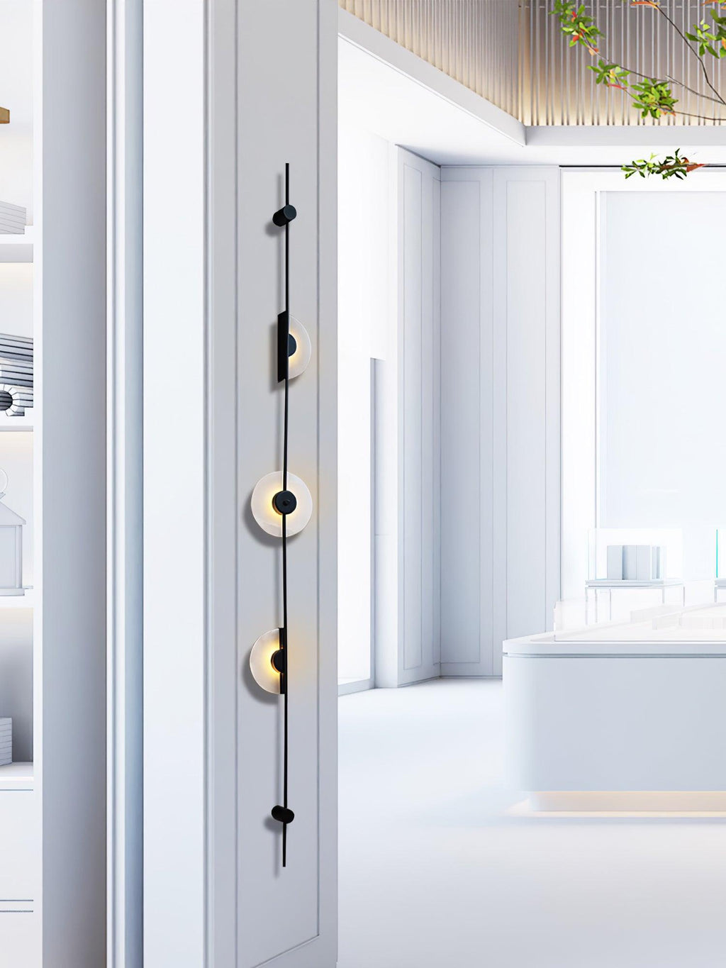 Black three-disc Clérachic sconce on a white wall edge, with a bright, pale showroom space stretching behind it.