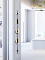 Black three-disc Clérachic sconce on a white wall edge, with a bright, pale showroom space stretching behind it.