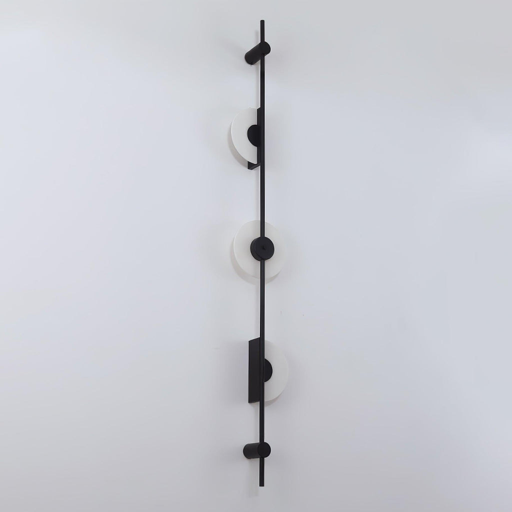 Black three-disc Clérachic sconce on a white wall, with its alabaster discs unlit, viewed at a slight angle.