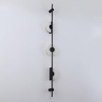 Black three-disc Clérachic sconce on a white wall, with its alabaster discs unlit, viewed at a slight angle.