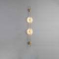 Gold Clérachic sconce with two glowing alabaster discs on a plain grey wall, a slim rod running above and below.