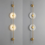 Two gold Clérachic sconces on a grey wall, a two-disc model lit on the left and the same unlit on the right.