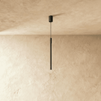 Side view of the Clérachic vertical black pendant shows its ribbed metal rod suspended on a fine black cable.