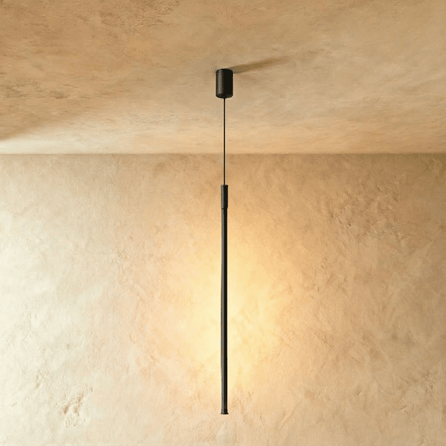 Another Clérachic black rod pendant drops from a perforated ceiling canopy, its warm glow lighting the wall below.