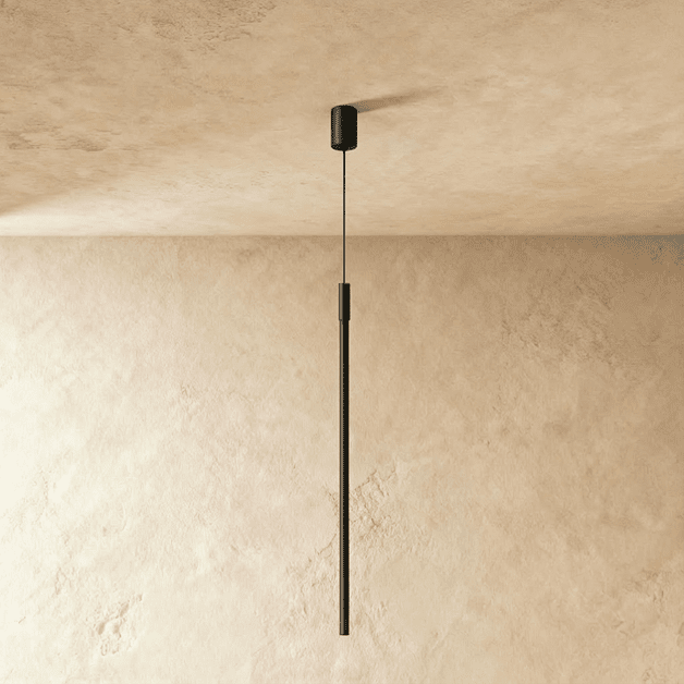 This Clérachic black pendant rod hangs plainly against plaster, its textured cylinder joint catching soft light.