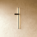 Clérachic slim black LED light bar on a limewash wall, its glowing vertical line held by a small horizontal bracket.