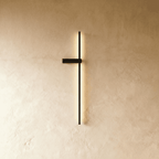 Clérachic slim black LED light bar on a limewash wall, its glowing vertical line held by a small horizontal bracket.