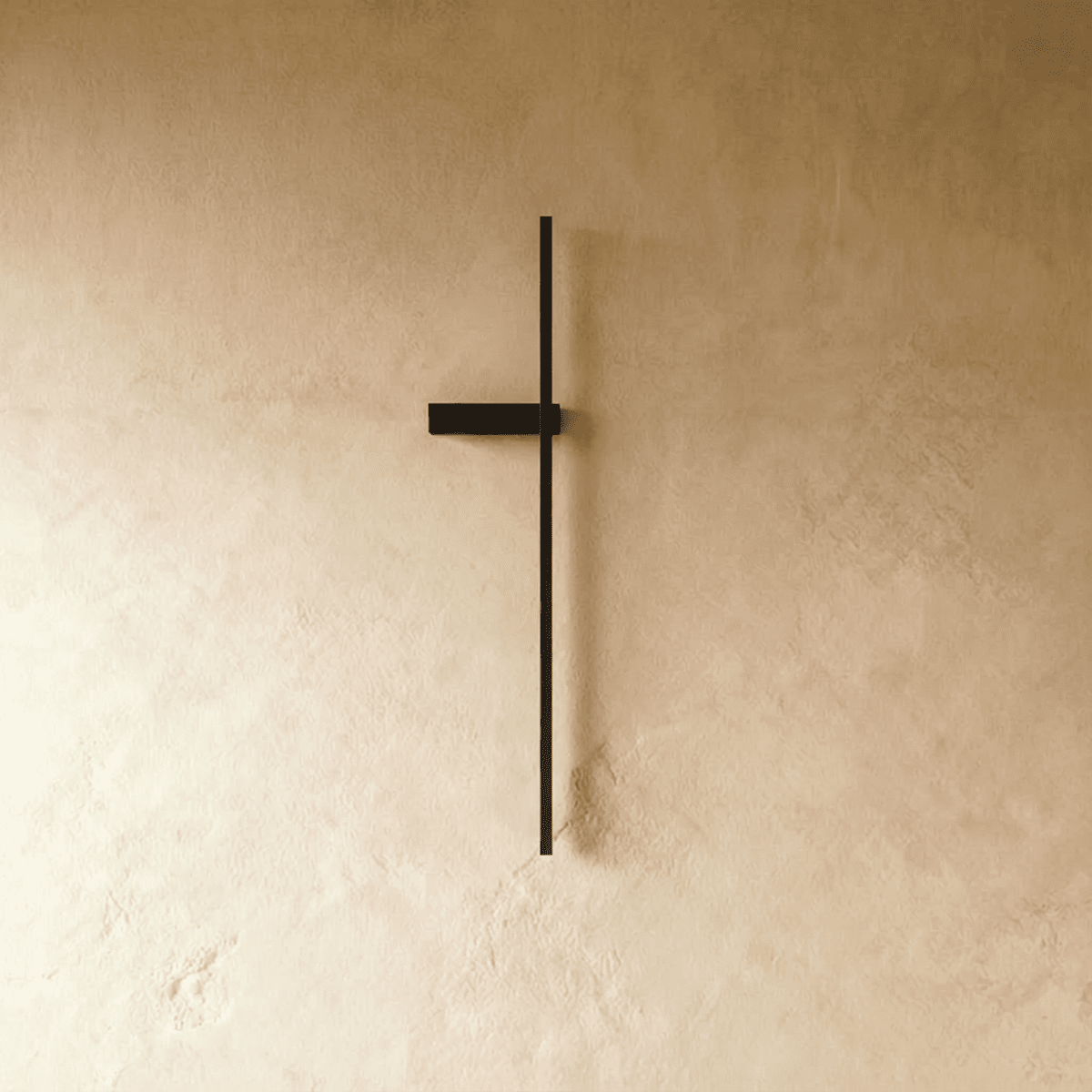 Clérachic slim black vertical light bar shown switched off on a limewash wall, with a short horizontal bracket at one side.