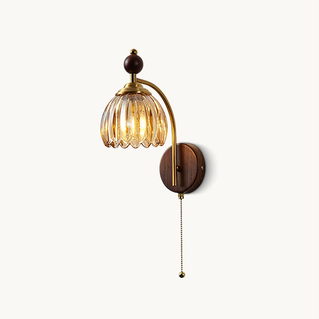 A Clérachic wall light with a ribbed amber glass shade, a brass arm, a wooden sphere and a pull chain, on a white backdrop.