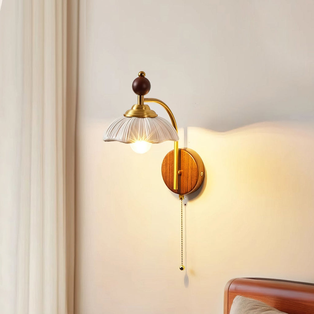 White ribbed resin shade on a Clérachic wall light with a brass arch and walnut backplate, glowing beside a curtain and a bed.