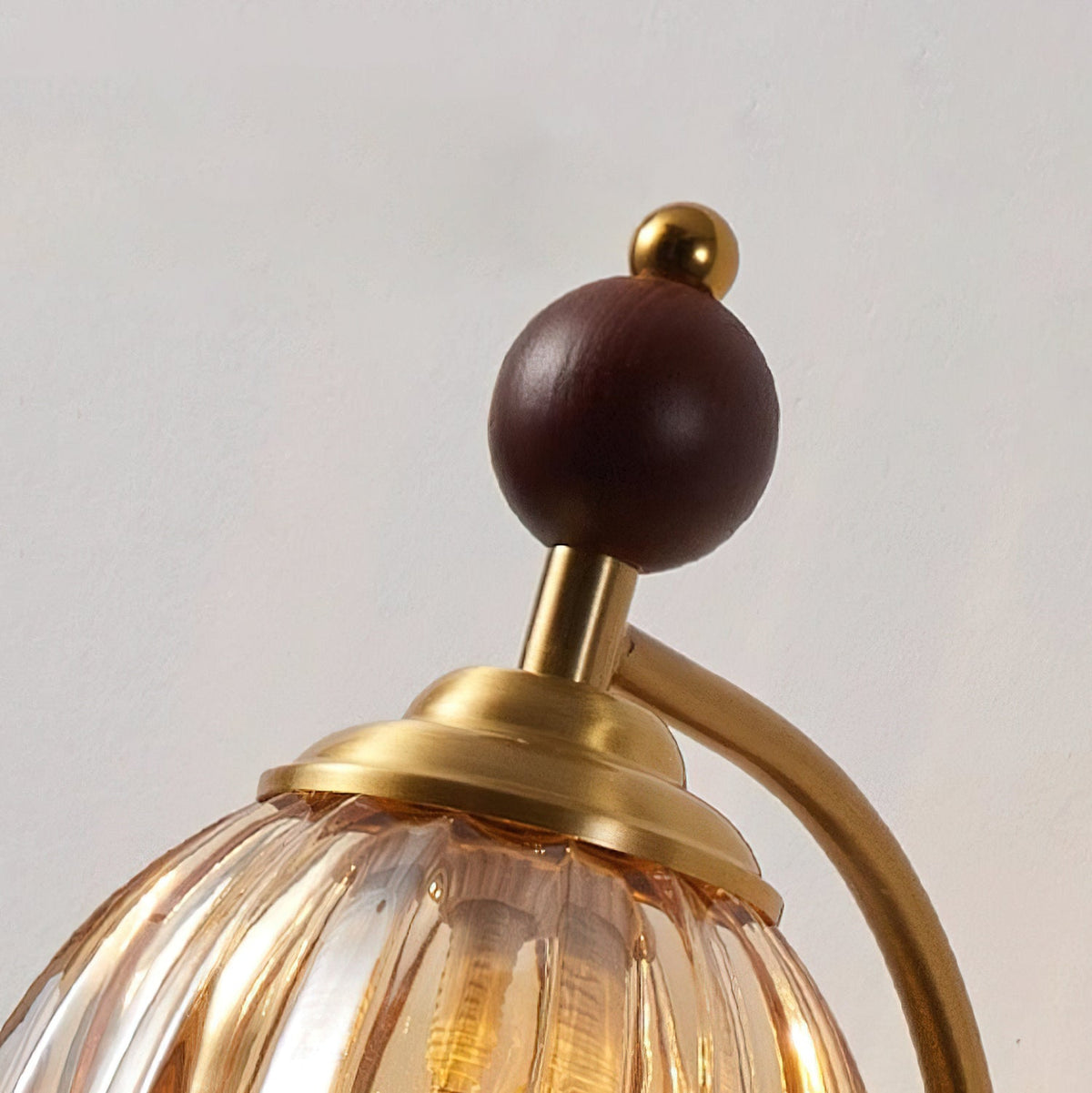 Close view of the wooden sphere, brass cap and ribbed amber glass of this Clérachic wall light.