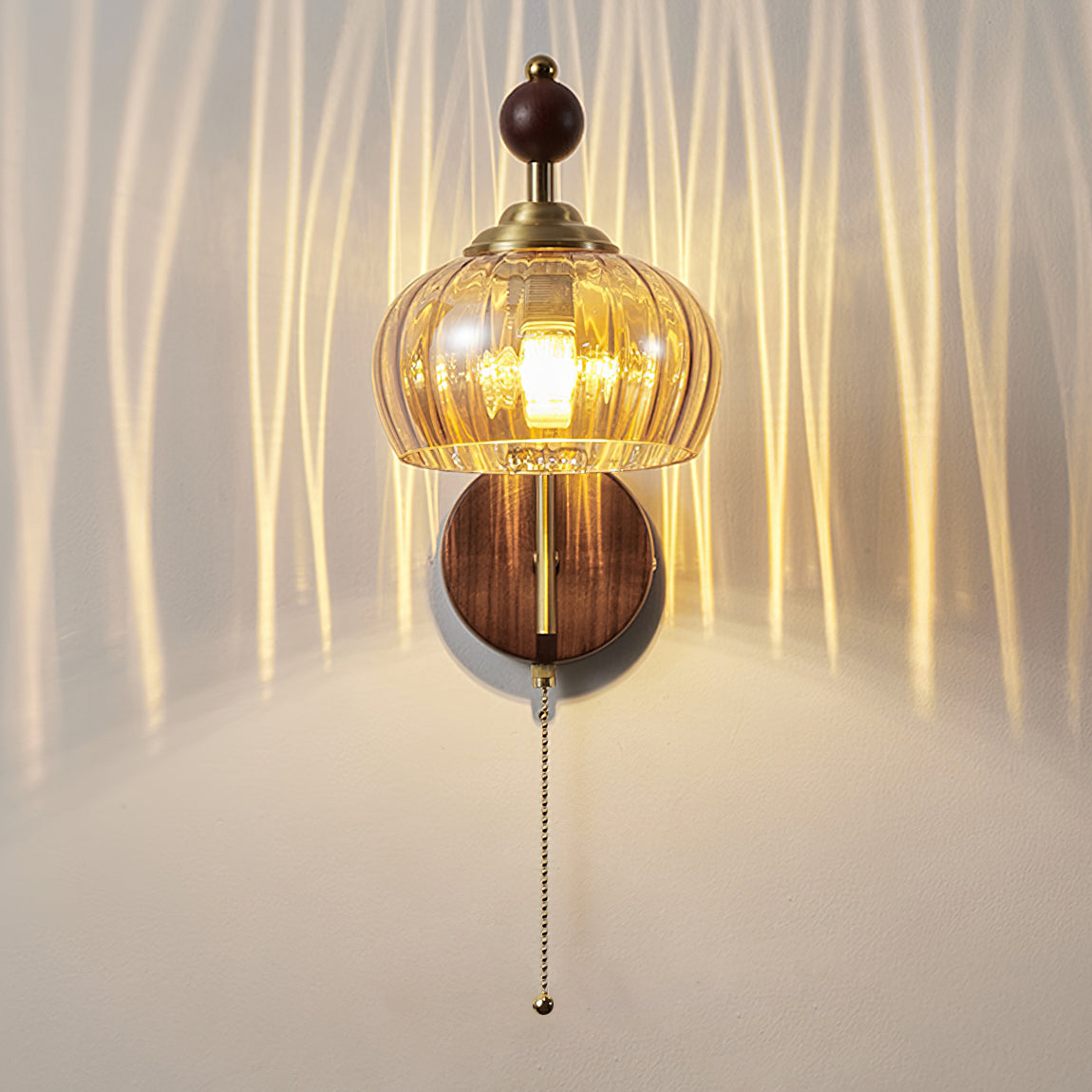 A lit Clérachic wall light with an amber glass shade, casting streaks of warm light up a pale curved wall.