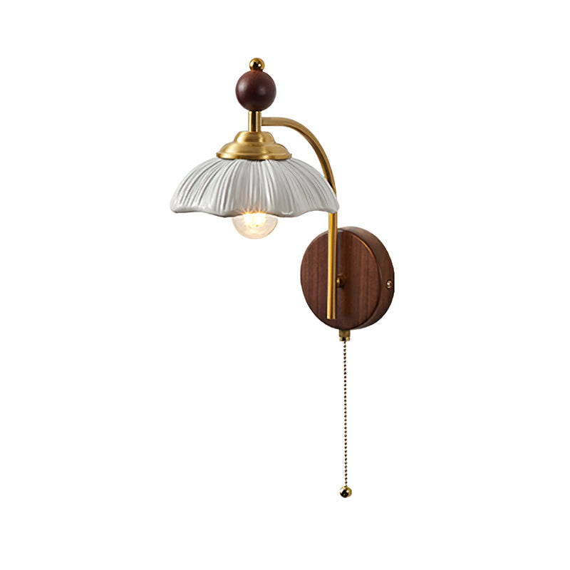 A white scalloped-shade Clérachic wall light with a brass arch, a walnut backplate and a pull chain, on white.