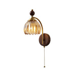 Clérachic wall light with a ribbed amber glass shade, a brass arch and a walnut backplate, on a white background.