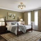 Hanging above a dark wooden four-poster bed in an olive-walled bedroom, this Clérachic ceiling light has a floral brass band.