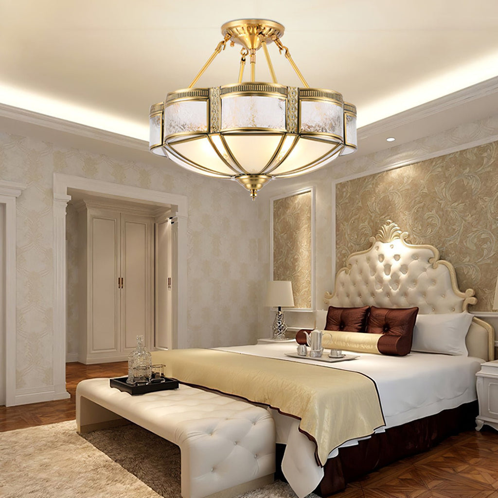 Hung from brass arms above a bed with a carved headboard, this Clérachic ceiling light glows beneath a softly lit ceiling recess.