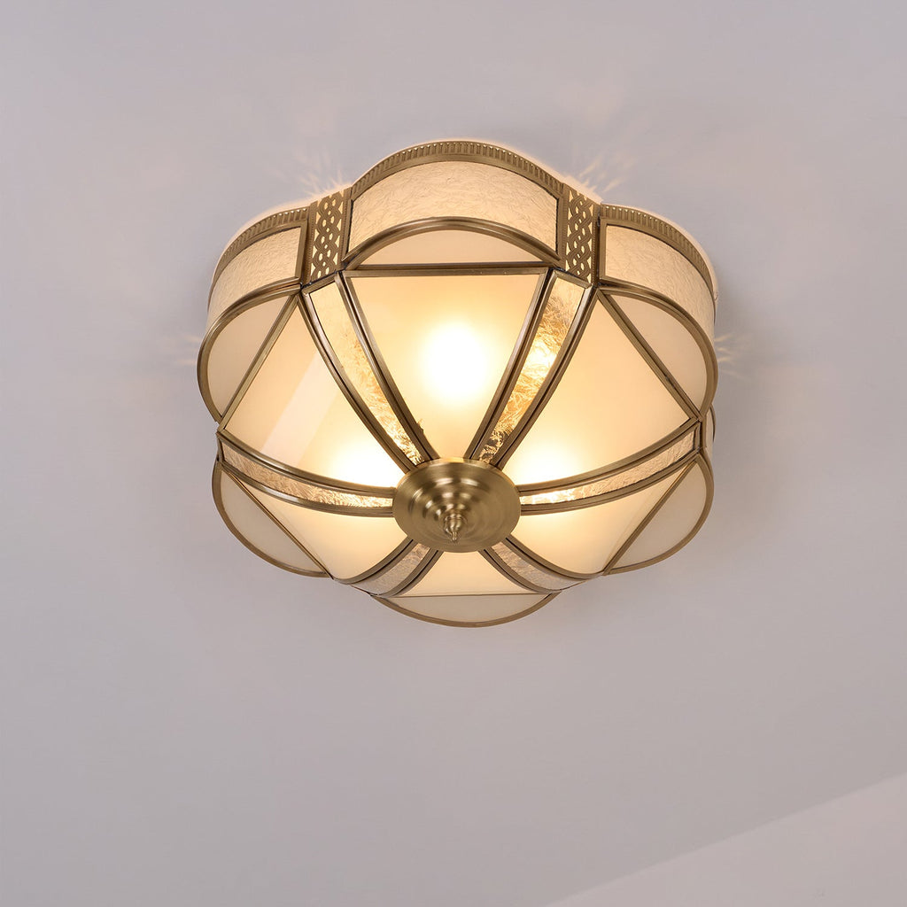 Switched on, this Clérachic flush ceiling light shows its brass-framed glass segments glowing warm, with bulbs visible through the glass.