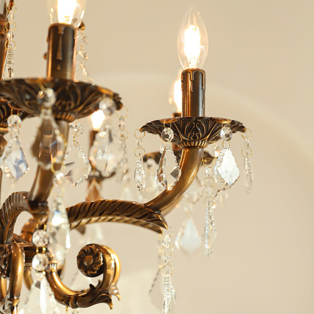 Close view of the cast bronze arms, candle cups and clear glass drops on this Clérachic chandelier.