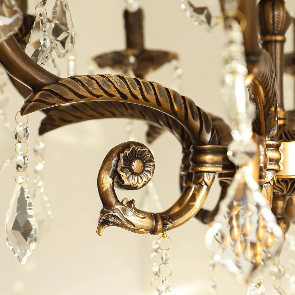 Close view of a leaf-ridged bronze arm ending in a scroll with a rosette on this Clérachic chandelier.