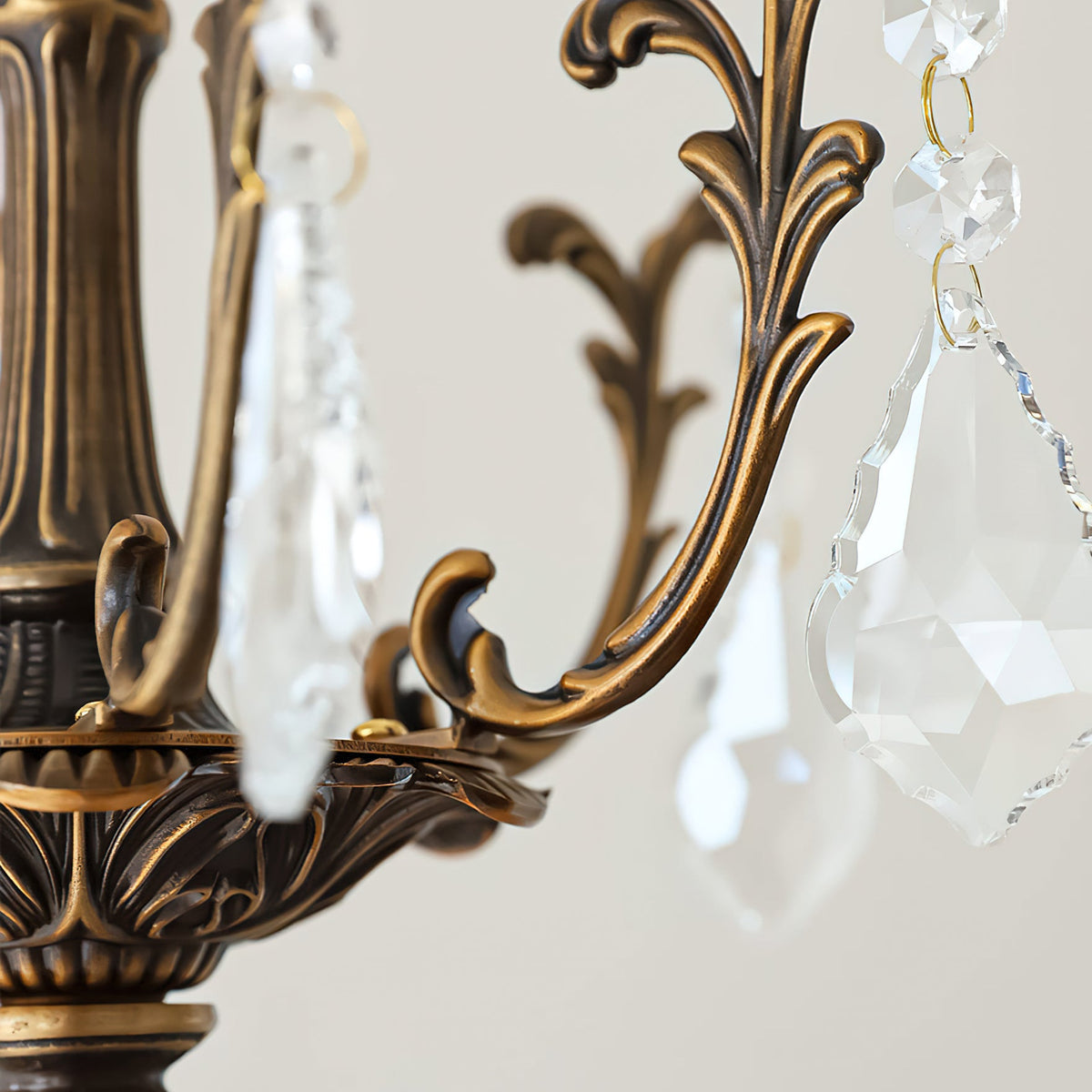 Close view of the bronze scrollwork and a large faceted clear prism on this Clérachic chandelier.