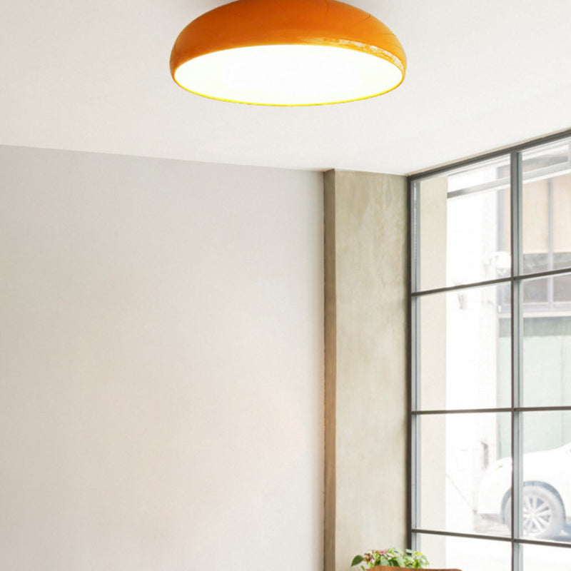 Orange Clérachic vintage dome ceiling light lit in a corner beside a large paned window.
