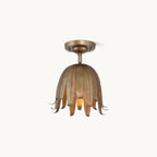 Clérachic flush-mount ceiling light in vintage gold, a bell of slim curled petals under a round canopy, on a plain white backdrop.
