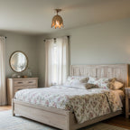 A Clérachic gold ceiling light with a warm glow in a sage-green bedroom, over a floral-covered bed and a pale wood headboard.