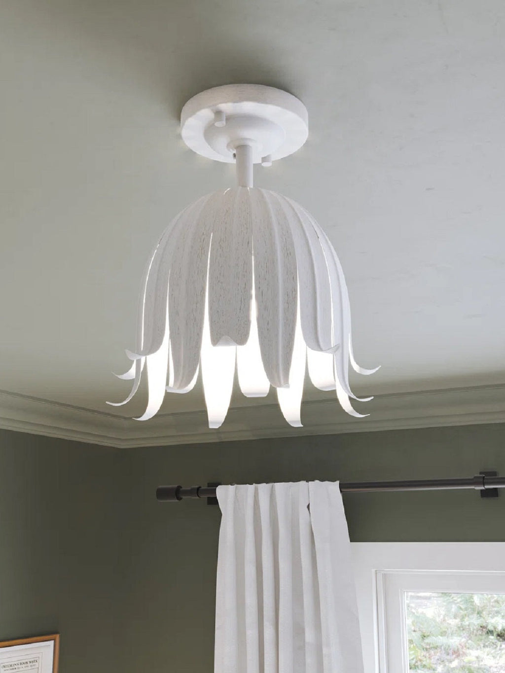 Close view of the Clérachic white petal ceiling light, its slim curled tips lit from inside, above a green wall and curtain.