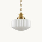 A Clérachic pendant with a ribbed white glass shade and brass cap, hung on a brass chain against a plain white backdrop.