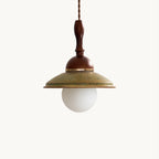 Clérachic pendant on a plain white backdrop, a green speckled ceramic shade under a turned walnut-coloured stem, with an opal globe bulb below.