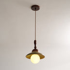 Clérachic pendant on its long twisted cord from a round walnut-coloured ceiling canopy, with the globe lit below the green shade.