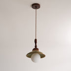 Unlit Clérachic pendant hanging from its round walnut-coloured canopy on a twisted cord, against a plain pale ceiling and wall.