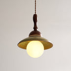 Lit Clérachic pendant, with the opal globe glowing warmly and lighting the yellow-green inside of its ceramic shade.