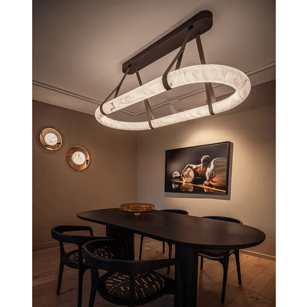 Clérachic Vista above an oval dining table, its bronze mounting bar and strap hangers echoing the dark timber below.