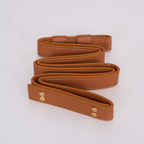 The Clérachic Vista tan strap option shown coiled, contrast stitching running the length of the faux leather.