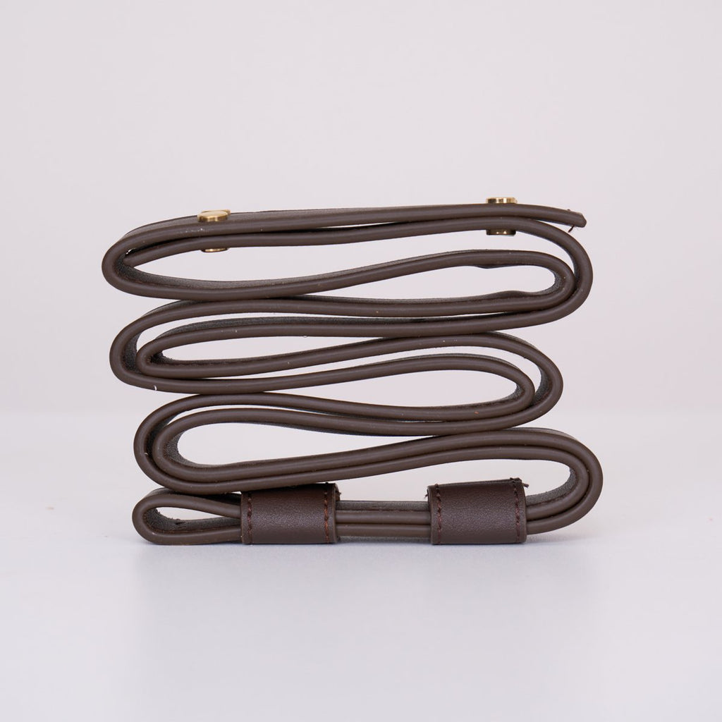 Clérachic Vista strapping in dark brown, looped and clasped with brass fittings on a plain white surface.
