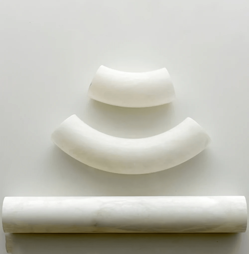 Clérachic Vista alabaster components arranged on white — two curved segments above one straight polished bar.