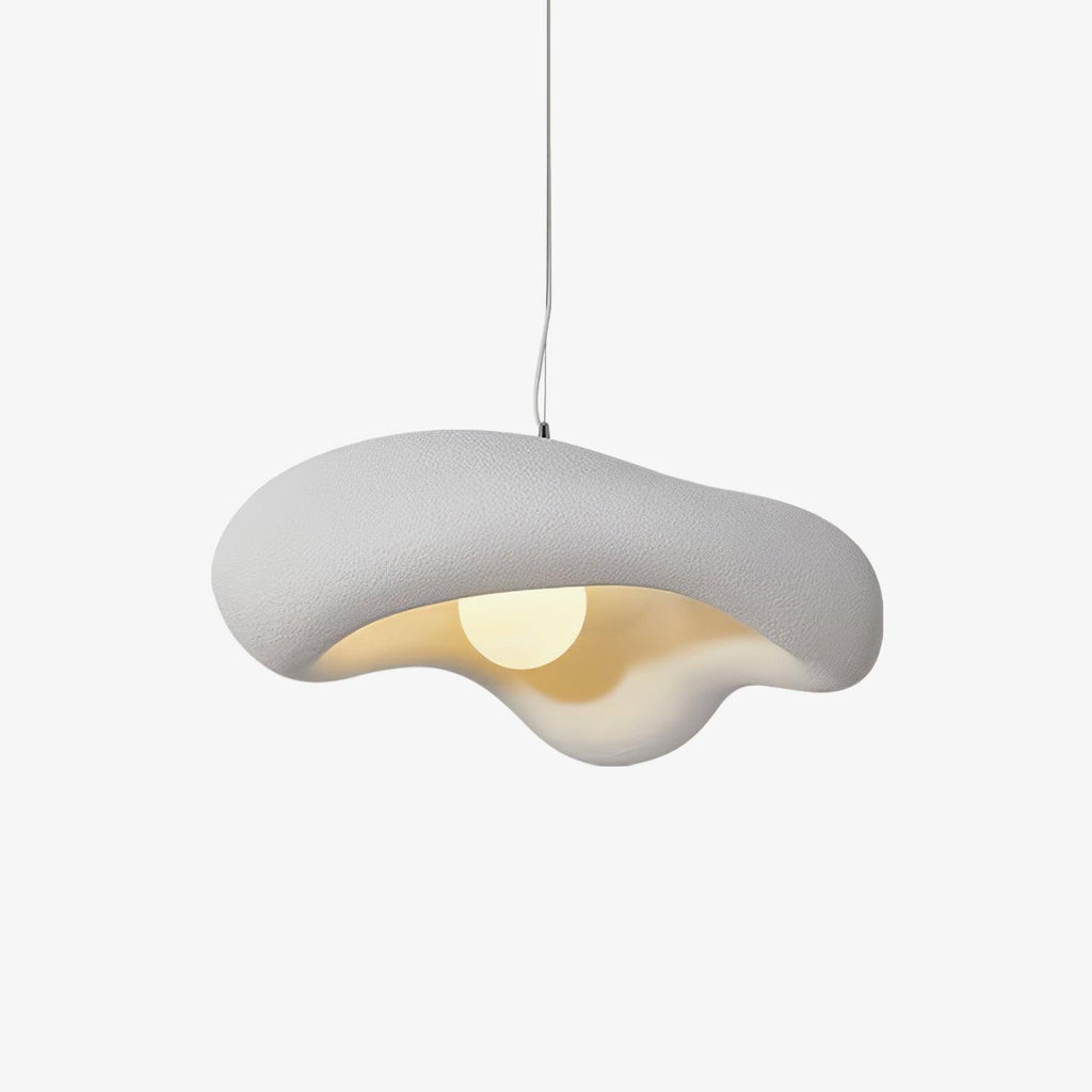 White Clérachic pendant with a rippled, organic shade on a plain white backdrop, a round bulb glowing in the cream-lit underside.