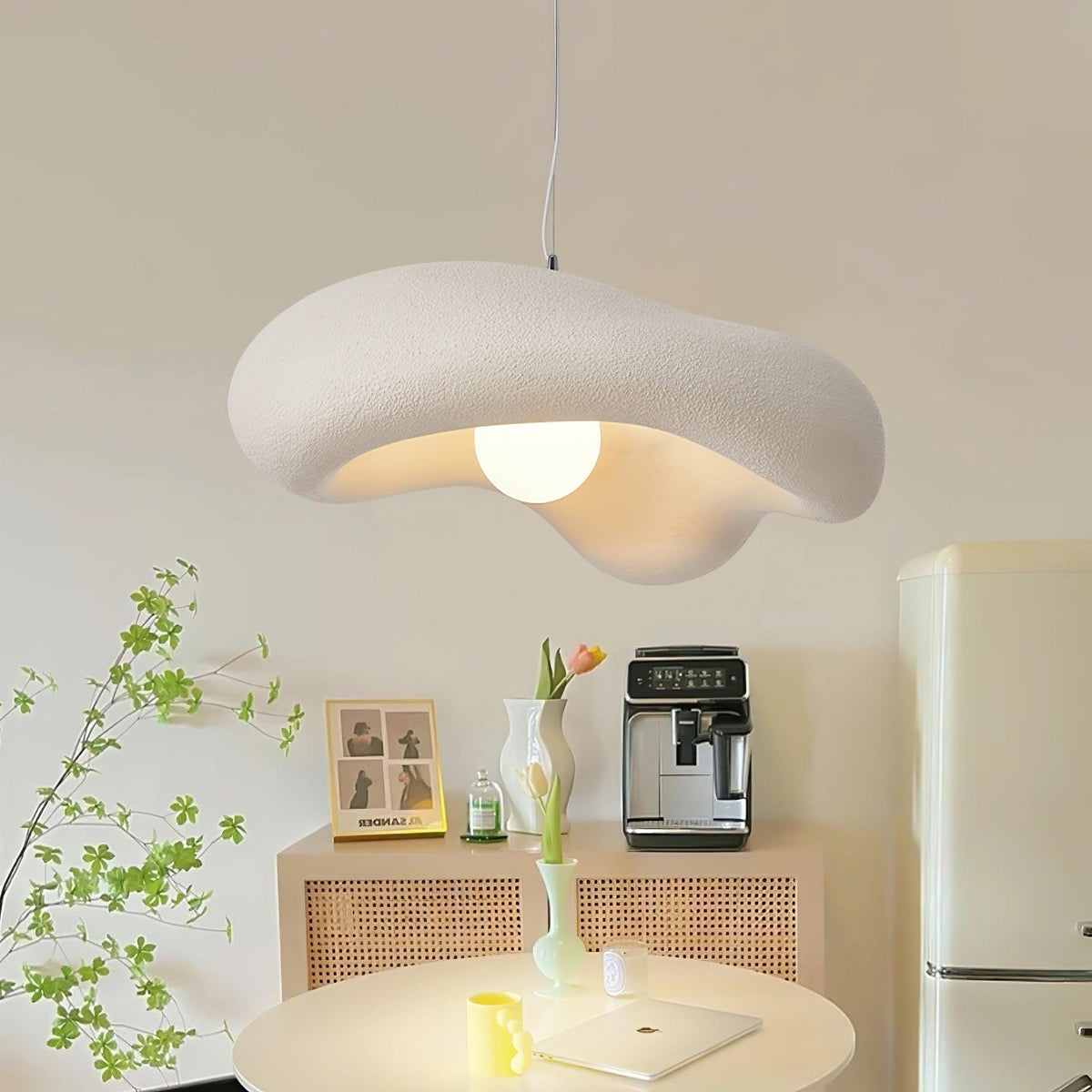 Clérachic pendant with a textured white shade hanging over a small round table, a coffee machine and rattan sideboard behind.