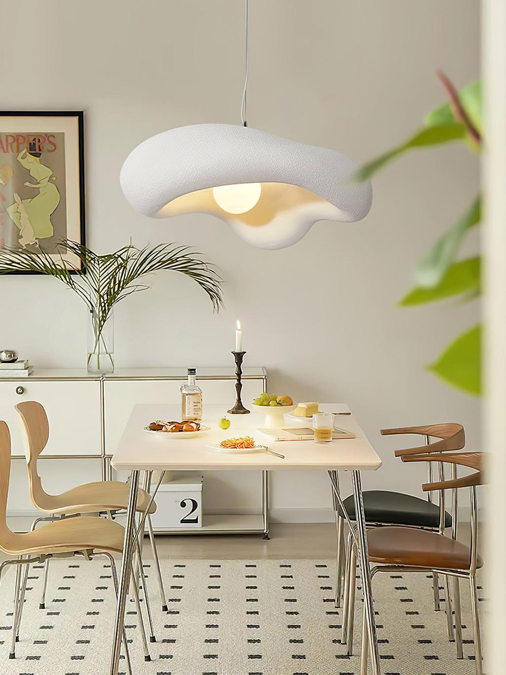 White Clérachic pendant above a laid dining table with wooden chairs and a framed print, seen in a narrow vertical crop.