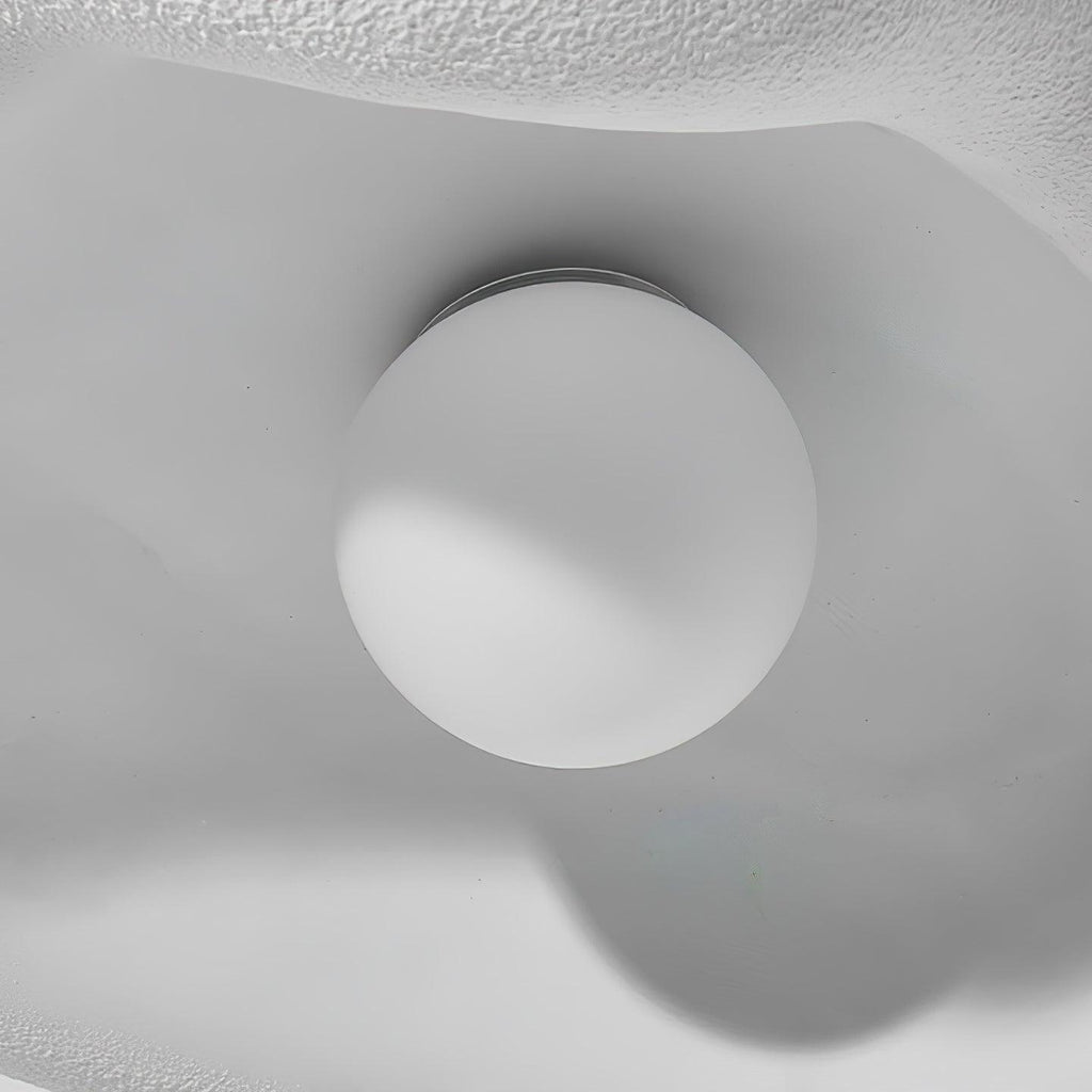 Close view from below of the round white bulb under the textured shade of this Clérachic pendant.