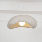 Beige Clérachic pendant with its rolled shade edge and a round bulb, in front of white wall mouldings.
