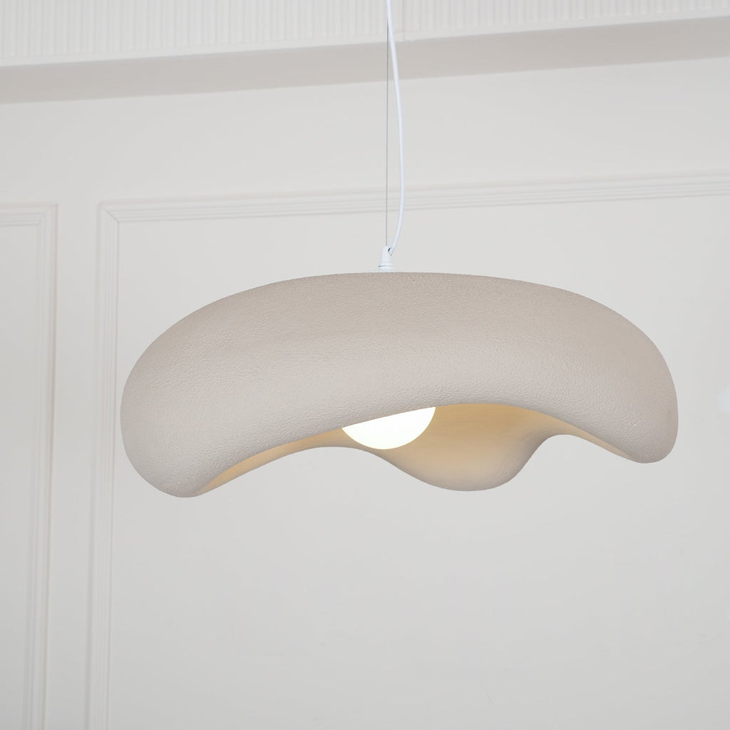 Beige Clérachic pendant seen from slightly below, its rough shade drooping on one side over a lit bulb.