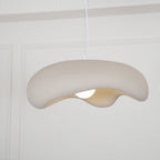 Beige Clérachic pendant seen from slightly below, its rough shade drooping on one side over a lit bulb.